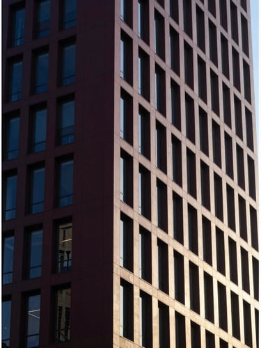 Architectural detail of a modern high-rise facade with high-contrast shadows and clean structural geometry, morning light.