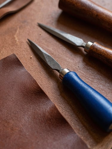 Close-up of traditional leather cutting and stitching tools in the Trujillo workshop, warm natural side-lighting emphasizing leather grain and authentic textures, shallow depth of field, 35mm