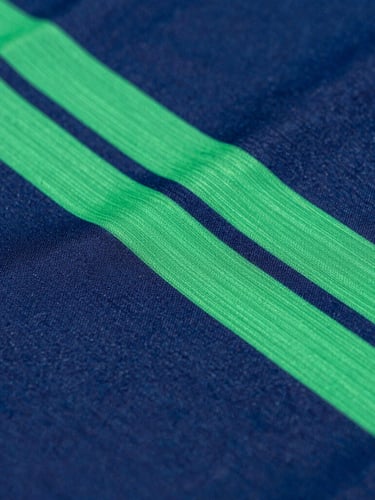 Detail macro shot of high-performance athletic fabric, vibrant sublimated green and blue geometric patterns, crisp studio lighting, deep navy background, sharp focus, 35mm
