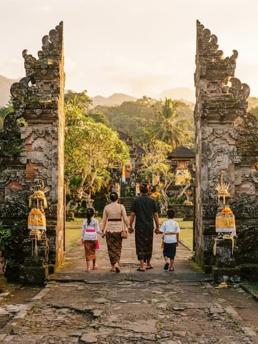 Warm environmental travel photography of a family walking through a sun-drenched Balinese temple gateway, soft morning light, 35mm