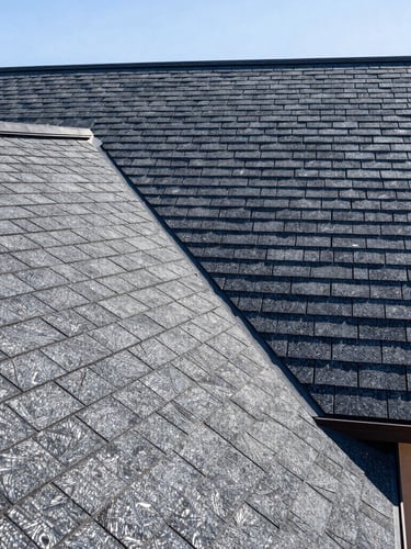 Close-up architectural shot of clean shingle alignments on a residential roof, high-contrast deep navy and steel tones, bright New Mexico sunlight
