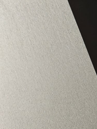 Extreme close-up of high-end textured heavy cotton paper with fine debossed lines, dramatic side-lighting, minimal editorial style, sharp focus