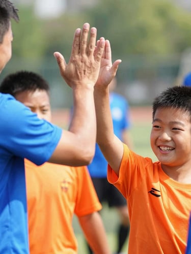 Close-up of a smiling child receiving a high-five from a volunteer coach on a bright sunny day, vibrant blue and orange sports shirts, joyful atmosphere.