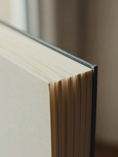 Macro close-up of deckled book edges and heavy cream paper stock under soft natural light