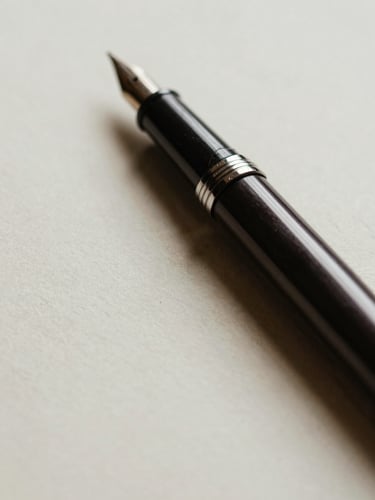 Close-up of a fountain pen resting on heavy deckled-edge paper, soft side lighting highlighting the texture of the cotton fibers, shallow depth of field