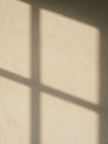 Abstract shadow of window panes falling on a warm plaster wall, quiet minimalist composition, architectural feel