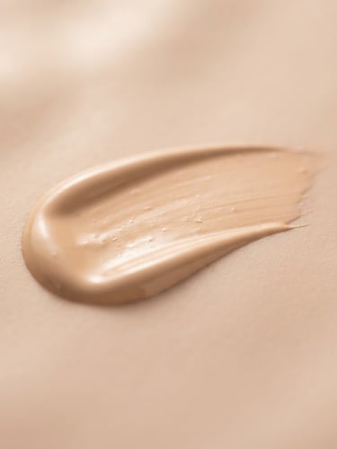 Macro shot of a pristine, silky liquid foundation swatch on a soft nude surface, elegant studio lighting, shallow depth of field