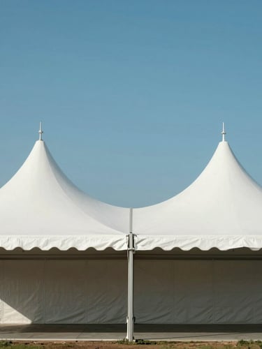 Symmetrical architectural shot of a massive, pristine white event tent structure erected under a clear blue sky, clean lines, bright daylight.