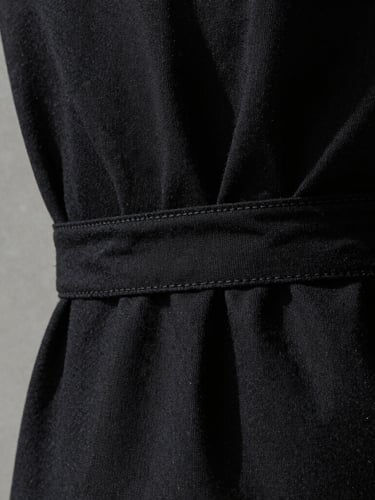 Stark minimalist fashion photography, extreme close-up of bound garment seams on heavy black cotton, high-contrast side-lighting emphasizing fabric weave texture, 35mm
