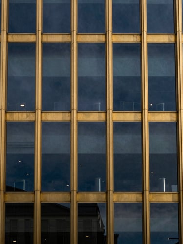 Macro high-contrast architectural detail of a gold-trimmed glass facade reflecting deep twilight sky