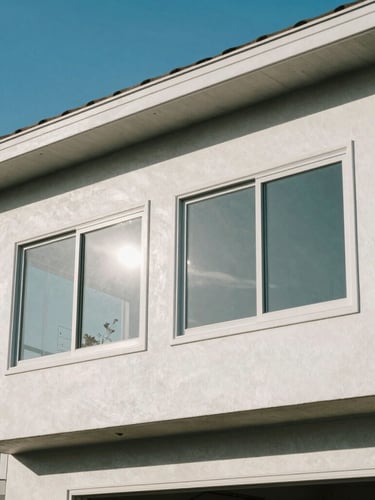 Bright Southern California sunshine reflecting off pristine windows of a coastal home, clean architectural lines, blue sky, wide crop.