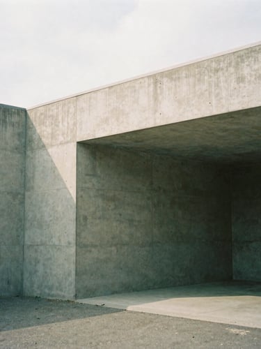 Tight architectural crop of a modern concrete workspace, soft overcast daylight, natural shadows, minimalist 35mm film style
