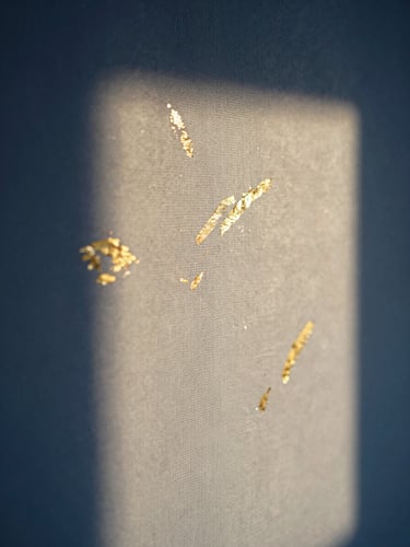 Vertical close-up of a textured canvas with gold leaf accents and dark blue pigments, twilight shadows