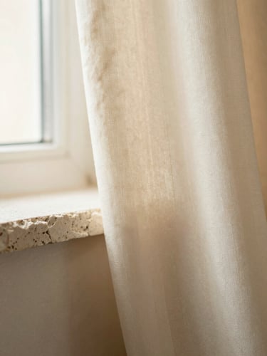 Extreme close-up of textured limestone and raw silk fabric catching soft morning window light, warm cream tones, 35mm.