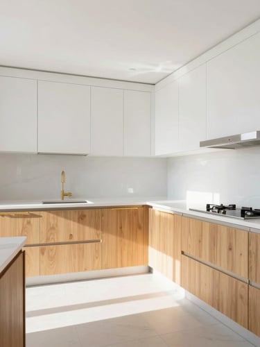 Bright architectural shot of a newly remodeled kitchen with clean white countertops, warm gold cabinet handles, and natural light streaming in, wide-angle framing.