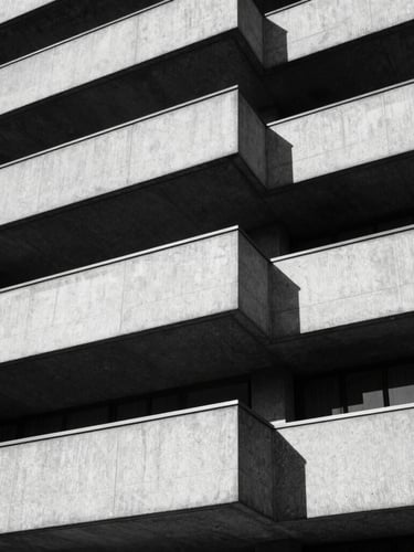 Stark black and white architectural detail of concrete London brutalist building, hard directional sunlight, deep sharp shadows, 35mm film