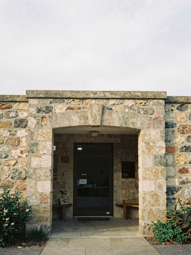 Medium-format film photo of an old stone community center entryway in soft overcast morning light, warm tones