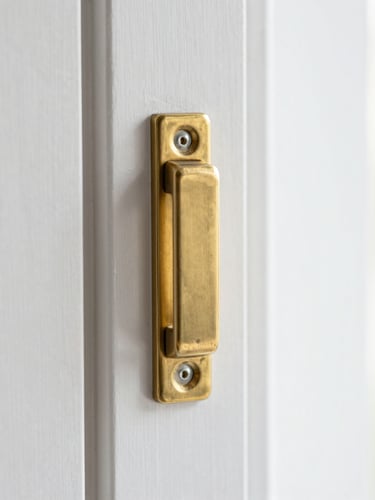 Macro top-down shot of a clean brass window latch on a pristine white frame, bright neutral daylight, high depth of field