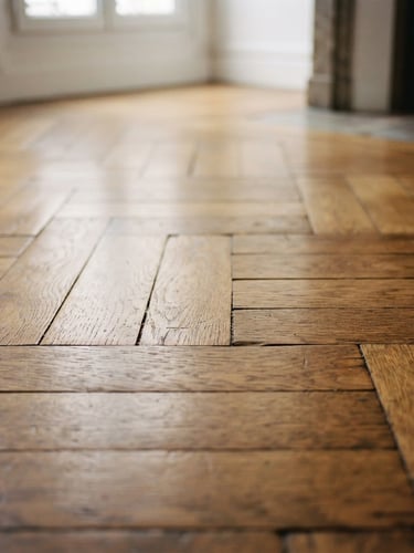 Close-up of a historic Lyon apartment parquet floor, warm oak wood grain, soft natural daylight filtering from high windows, shallow depth of field, 35mm photography