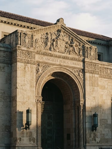 Dignified architectural detail of a classic stone library facade in Los Angeles, soft natural morning light casting long shadows, warm tones, 35mm film aesthetic