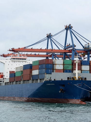 Wide environmental shot of a massive container cargo ship docked at a deep-water port terminal under cool overcast daylight