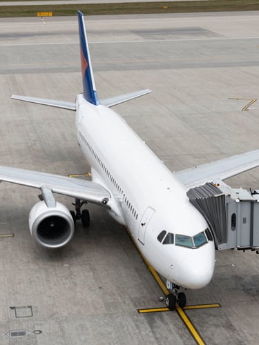 Bird's-eye view of a commercial aircraft parked at a tarmac gate, clean overcast daylight, no shadows, minimal airport ground markings visible below the wing