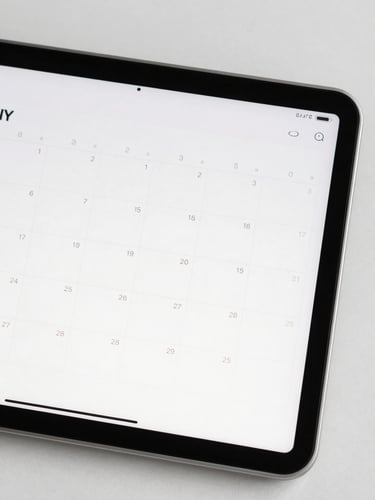 Close-up of a modern tablet displaying a clean calendar and task list, neutral background, sharp focus, bright daylight.