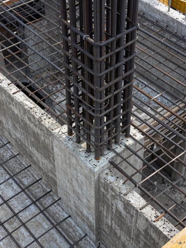 Close-up overhead shot of reinforced concrete formwork and rebar grid on a commercial foundation pour, natural overcast daylight, no shadows, tight framing showing tie wire intersections and spacing pattern, no people