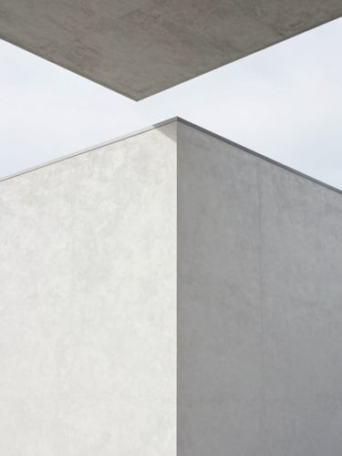 Architectural detail of a freshly completed minimalist plaster wall meeting a concrete ceiling under bright overcast Belgian daylight, razor-sharp lines, clean geometric angles, 35mm lens.