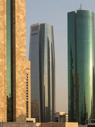 Warm environmental architectural shot of Riyadh financial district at golden hour, modern limestone and glass skyscrapers, soft desert sunlight casting long shadows, medium format