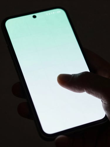 Macro top-down shot of a hand interacting with a premium dark Android phone, displaying a minimalist grid interface with neon-mint accents, moody low-key studio lighting, soft rim highlights on the device bezel.