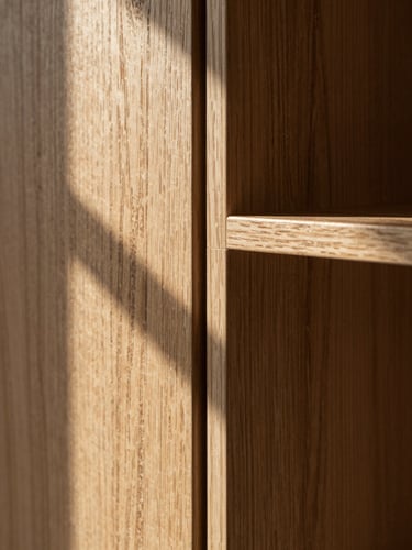 Extreme close-up of a flush panel-to-panel joint in smoked oak built-in shelving, shadow line razor-thin, natural north light raking across the grain, no people, architectural framing