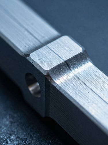 Macro close-up of a machined titanium component with visible tool paths, sharp metallic edges, cool blue industrial lighting, 50mm lens
