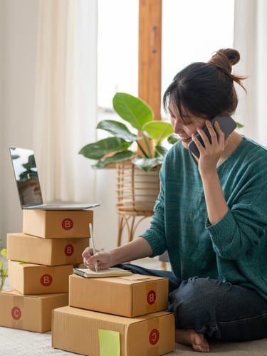 Una emprendedora que gestiona un negocio de comercio electrónico desde casa, hablando por teléfono