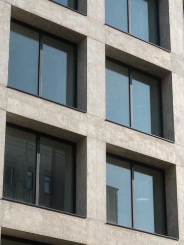 Close-up of a modern building facade with clean concrete lines and large windows under bright daylight