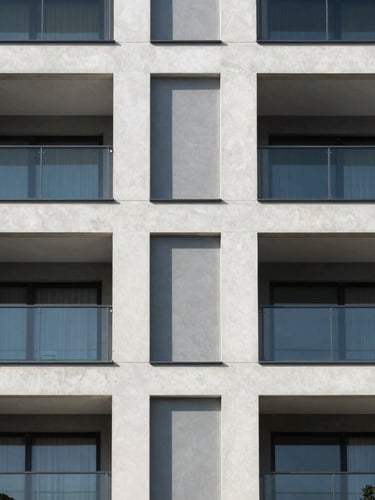 Symmetrical architectural crop of a modern residential building facade with clean concrete lines and glass balconies, bright natural daylight, sharp shadows, minimalist composition