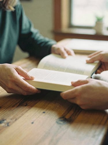 Candid medium shot of hands sharing books over a rustic cedar table, warm indoor community lighting, 35mm film style.