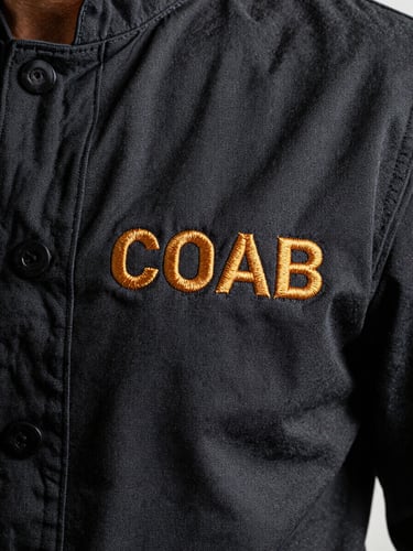 Close-up of high-density brand embroidery on the chest of a dark chef jacket, sharp details of the tight stitching