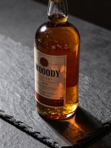 Moody close-up of a vintage bottle of spirits resting on a dark slate counter, dramatic side-lighting casting long shadows, rich amber liquid.