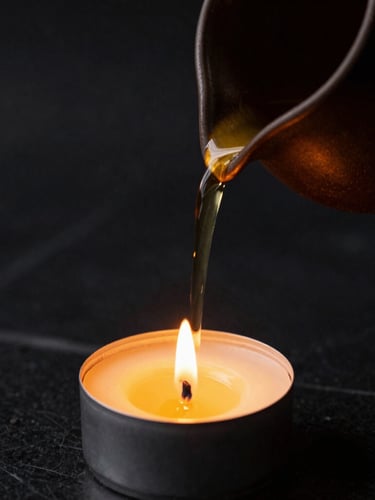 Close-up of warm oil being poured from a dark ceramic vessel, soft golden candlelight, matte black marble background, shallow depth of field, 35mm