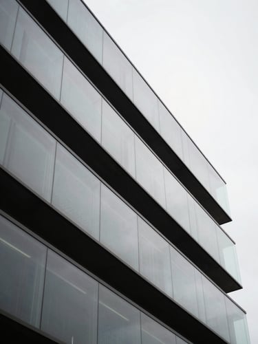 An abstract macro photograph of modern architectural glass panels in Nova Lima, sharp diagonal lines, deep shadows, soft overcast daylight, professional medium format.