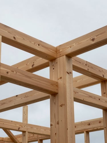 Clean architectural shot of exposed Douglas-fir timber framing against an overcast Pacific Northwest sky, showing precise joinery and structural integrity.