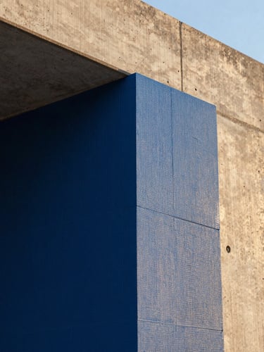 A detailed close-up of premium blue thermal insulation boards being installed on a concrete wall structure, golden-hour light highlighting the architectural precision.