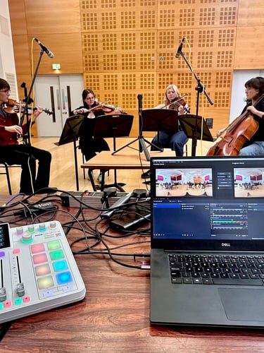 A string quartet recording in a studio with an audio mixer and laptop for live streaming.