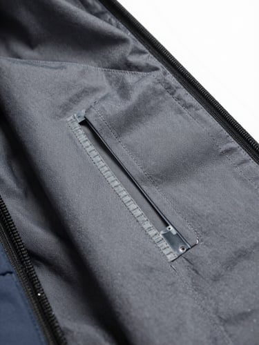 Macro close-up of a technical waterproof jacket interior, showing precise heat-sealed seam tape over gray fabric, clinical bright lighting, studio setting