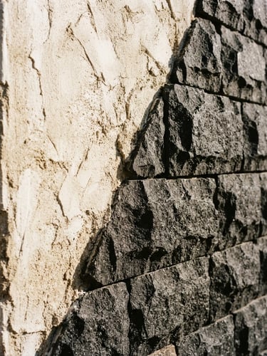 An abstract architectural detail of raw plaster meeting chiseled basalt, high-contrast sunlight casting deep shadows, 35mm film