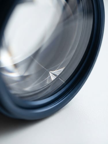 Abstract close-up of light refracting through clean curved glass lens, soft natural daylight, clinical minimalism