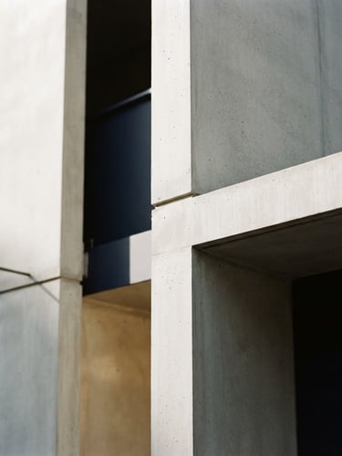 Close-up of elegant minimalist architectural concrete lines with deep shadows, soft natural daylight, warm champagne accents, 35mm photography