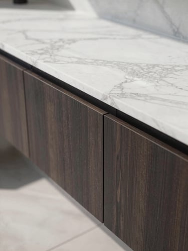 Close-up architectural detail of a premium marble slab meeting custom dark wood millwork with millimeter precision, bright natural daylight, sharp shadows