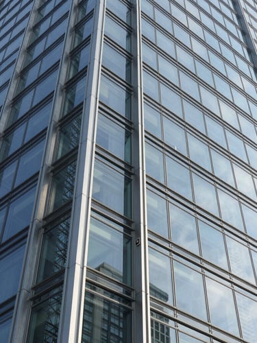 Macro shot of a structural glass joint on a modern skyscraper facade, crisp natural daylight, sharp geometric shadows, steel and glass textures, wide-angle lens